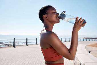 黑色的女人喝水<strong>瓶</strong>健身锻炼培训锻炼海滩<strong>海洋</strong>海夏天位置微笑快乐体育跑步者喝医疗保健健康复苏