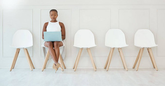 年轻的集中非洲美国女商人工作移动PC等待面试坐着椅子白色墙等待面试办公室