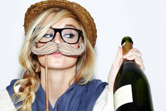 好玩的面部头发特写镜头年轻的女人持有瓶香槟持有胡子道具脸