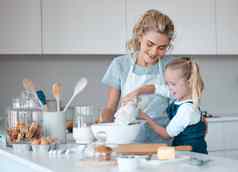 女孩倒面粉碗年轻的孩子筛选面粉碗快乐妈妈。帮助女儿烤高加索人妈妈。烘焙女儿厨房家庭烘焙
