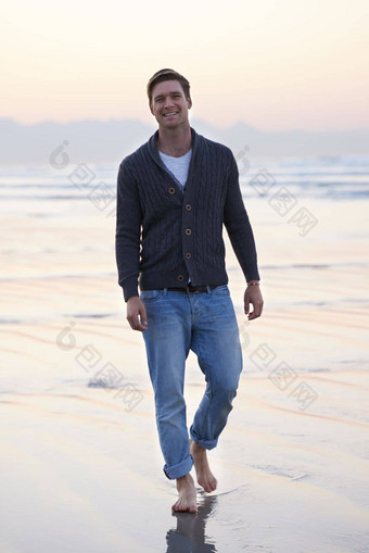 享受走海滩全身的肖像英俊的年轻的男人。走海滩