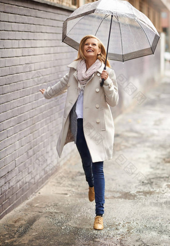 享受走雨年轻的金发女郎女人持有伞走市中心雨