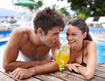 分享喝有吸引力的年轻的夫妇分享鸡尾酒边缘池