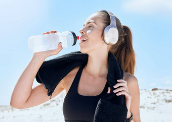 海滩锻炼喝水耳机音乐锻炼健身培训打破健康放松体育运动女人流媒体音频休息身体有氧运动水水合作用