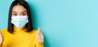 科维德社会距离流感大流行概念关闭年轻的亚洲女人医疗面具显示拇指赞美好提供站蓝色的背景
