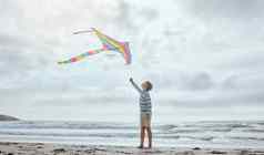 高加索人男孩飞行色彩鲜艳的彩虹风筝风海滩好玩的年轻的孩子有趣的在户外是清白的童年