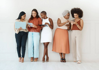 集团多样化的年轻的女商人站墙办公室科技快乐的同事们会说话的技术站行工作