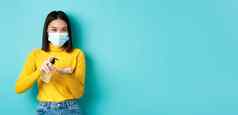 科维德社会距离流感大流行概念微笑亚洲女人医疗面具预防措施冠状病毒手洗手液站蓝色的背景