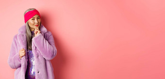 时尚购物概念时尚的亚洲夫人紫色的人造革外套<strong>感兴趣感兴趣</strong>促销活动微笑思考粉红色的背景