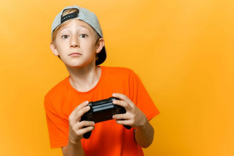 男孩帽橙色t恤持有手柄手玩电脑游戏
