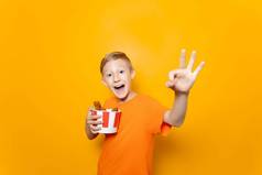 男孩橙色t恤持有纸桶鸡翅膀前面显示标志