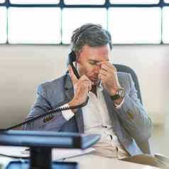 上了年纪的商人头疼电话调用办公室在线通信累了员工沮丧男人。头疼痛的最后期限压力员工焦虑企业电话调用