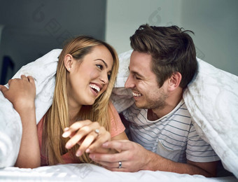 快乐使快乐快乐年轻的夫妇放松羽绒被床上