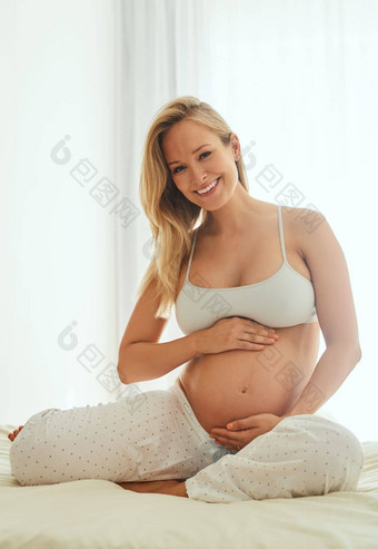 潜在的使美丽的的事情怀孕了女人触碰肚子坐着床上