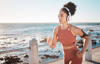 黑色的女人健身运行耳机海滩海点角小镇锻炼运动非洲美国女跑步者海洋海岸运行有氧运动培训锻炼