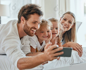 快乐家庭自拍智能手机卧室爱护理放松家庭首页早....微笑父母兴奋孩子们手机数字照片有趣的幸福生活方式