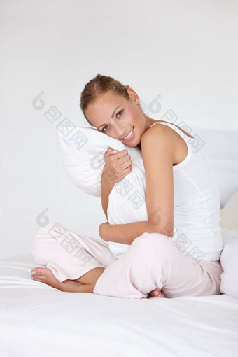 爱床上美丽的年轻的女人拥抱枕头床上