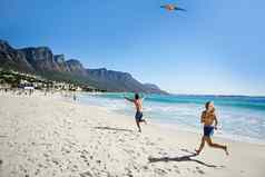 飞行风筝有趣的风趣的年轻的夫妇玩风筝享受一天海滩