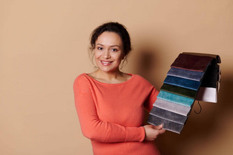 有吸引力的女人室内设计师微笑显示织物样品室内装潢材料相机米色背景