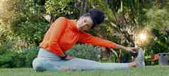 伸展运动平静呼吸女人草公园自然环境健身锻炼会话健康健康生活方式体育人肌肉放松锻炼坐着地面