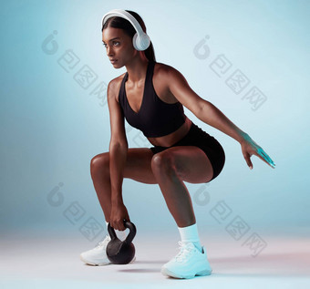 女人音乐健身伸展运动壶铃蓝色的背景工作室年轻的女运动员锻炼培训设备集中体育运动健康音频动机耳机