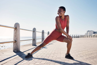 黑色的女人伸展运动腿海滩健身锻炼锻炼动机跑步者体育温暖的非洲女人快乐运动员运行健康目标有氧运动拉伸海洋人行道上