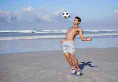 足球海滩年轻的肌肉发达的玩足球海滩