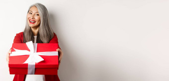 快乐假期概念快乐的亚洲高级女人给红色的礼物盒子微笑祝贺情人节一天站白色背景