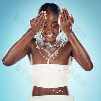 快乐女人水飞溅脸清洁护肤品卫生新鲜的身体健康化妆品美工作室蓝色的背景黑色的模型洗脸水滴面部淋浴