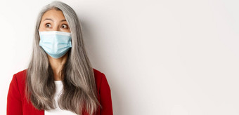 科维德流感大流行业务概念关闭优雅的亚洲高级夫人盯着上左角落里穿医疗面具冠状病毒白色背景