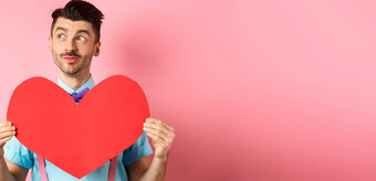 情人节一天概念梦幻浪漫的男人。左显示大红色的心断路站粉红色的背景