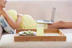 健康的零食放松健康的餐怀孕了女人说谎沙发上移动PC