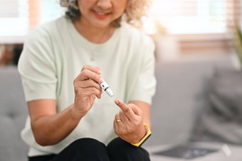 裁剪拍摄糖尿病成熟的夫人采取血样本《柳叶刀》笔糖尿病上了年纪的医疗保健概念