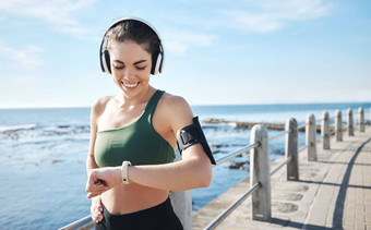 耳机智能手表女人运行锻炼锻炼健康结果进步健身步骤目标检查小时体育人海滩听音乐播客培训