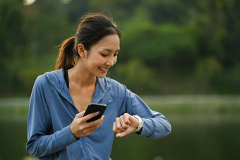 愉快的运动女人检查心率数据智能手表运行公园健康的生活方式概念