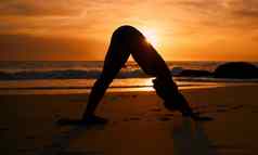瑜伽轮廓向下狗日落海滩海洋海锻炼放松锻炼培训瑜珈女人沙子伸展运动日出医疗保健健康健身普拉提强大的身体