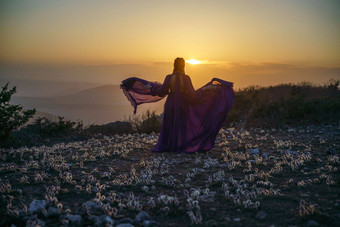 日落紫色的衣服女人山上升神秘的日落云女孩长紫色的衣服草地草梦想紫色的花