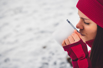 关闭女人喝茶金属杯白色雪冬天森林走