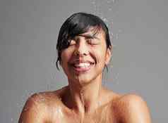 感觉恢复活力的洗澡工作室拍摄年轻的女人享受淋浴灰色的背景