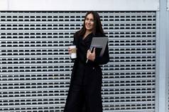 肖像成功的业务女人移动PC杯咖啡背景铝网墙