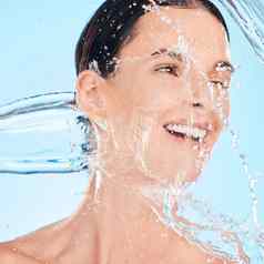 水飞溅快乐女人淋浴清洁脸身体护理梳理早....例程蓝色的背景护肤品健康的模型微笑洗美健康工作室