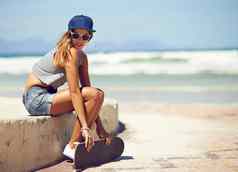 保持很酷的夏天年轻的女人挂木板路滑板