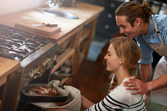 生活新鲜的烤面包年轻的夫妇检查面包烤箱