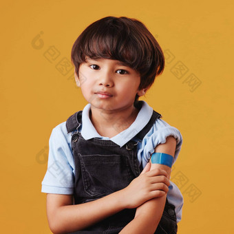 肖像亚洲男孩持有手臂显示邦迪牌创可贴孩子穿石膏强迫疫苗伤心孩子注射橙色背景