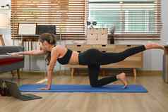 活跃的年轻的女人运动服装平衡表格构成锻炼席练习瑜伽首页