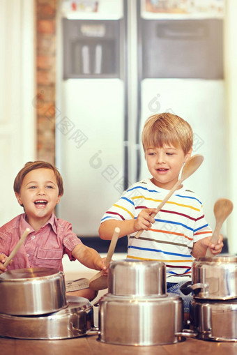 人准备好了震撼年轻的男孩坐着厨房地板上玩锅锅