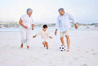 活跃的爷爷奶奶玩足球海滩孙子男孩踢球祖母祖父海岸