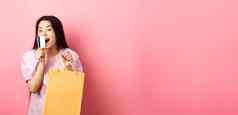 购物兴奋美丽的亚洲女人购买商店持有纸袋接吻塑料信贷卡站粉红色的背景