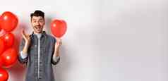 情人节一天概念快乐的年轻的男人。庆祝爱假期站红色的心气球惊讶尖叫快乐白色背景