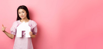 真正的<strong>房地产</strong>保险概念美丽的亚洲女人指出纸房子断路显示机构标志站衣服粉红色的<strong>背景</strong>